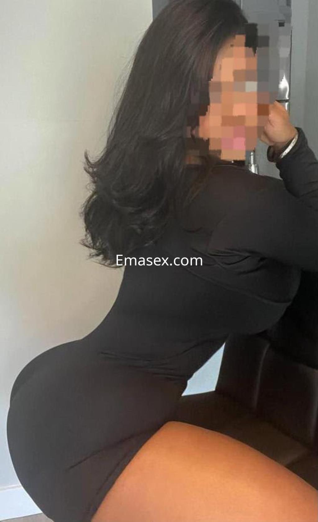 Puta en Pontevedra, posando de perfil con un vestido negro ceñido que resalta sus curvas y cabello largo.
