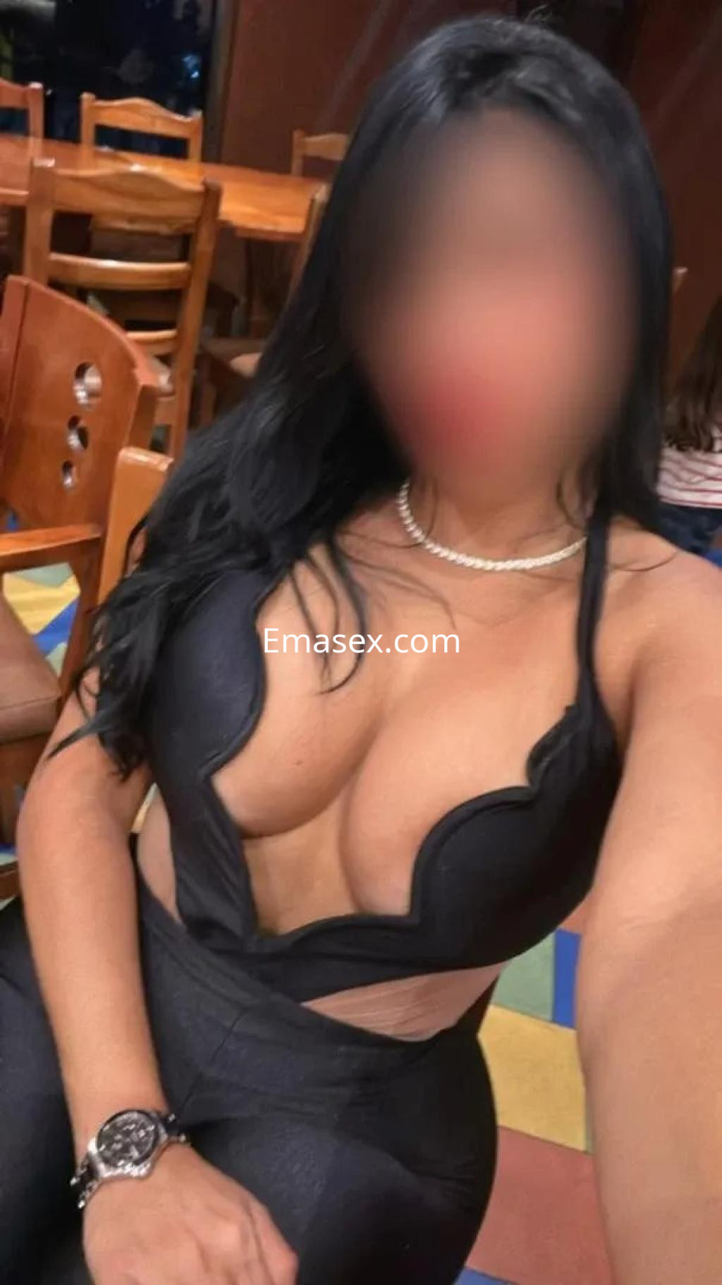 Puta en Zaragoza viste un ajustado conjunto negro que resalta su figura en un ambiente de bar.