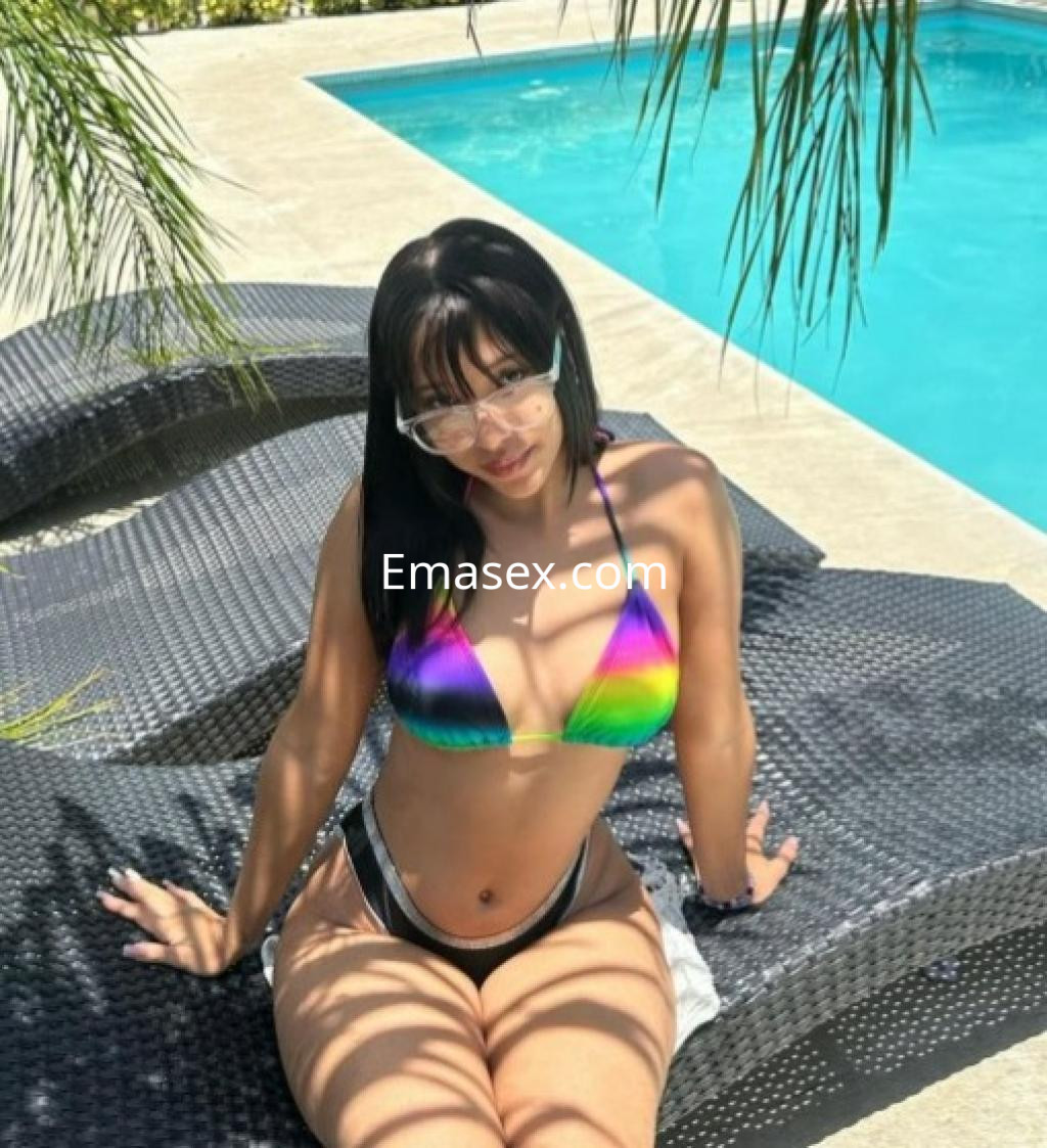 Puta en Pontevedra, posando en bikini de colores brillantes junto a una piscina, con gafas de sol y cabello oscuro.
