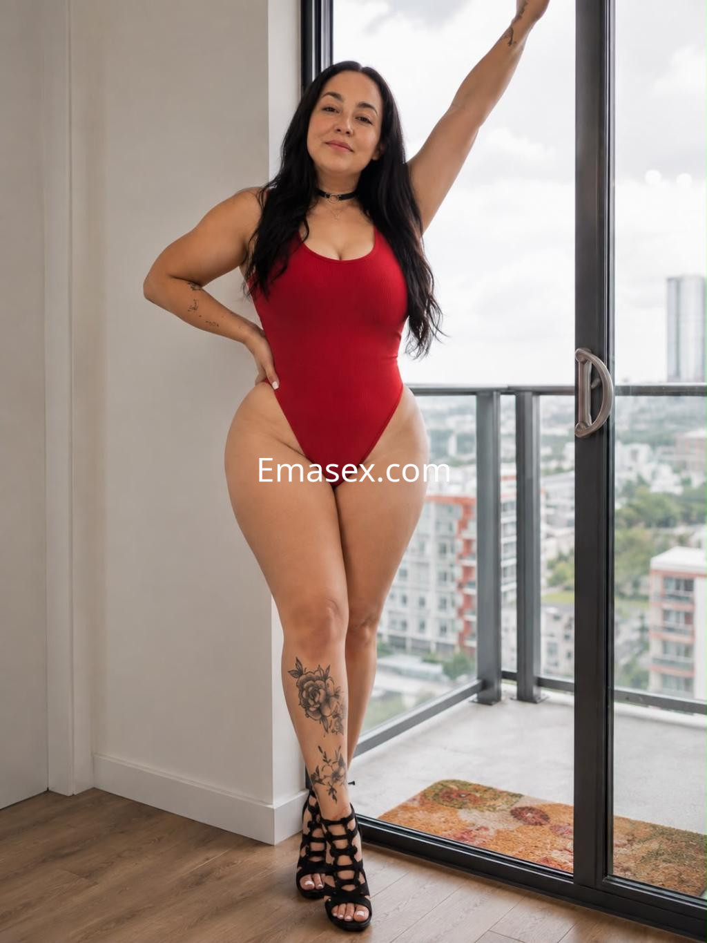 Puta de Bilbao posando con un traje de baño rojo, destacando su figura y tatuajes en un entorno moderno.
