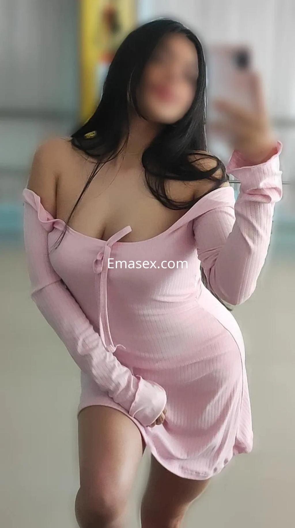 Puta en Barcelona posando con un vestido rosa claro que resalta su figura y muestra sus hombros.