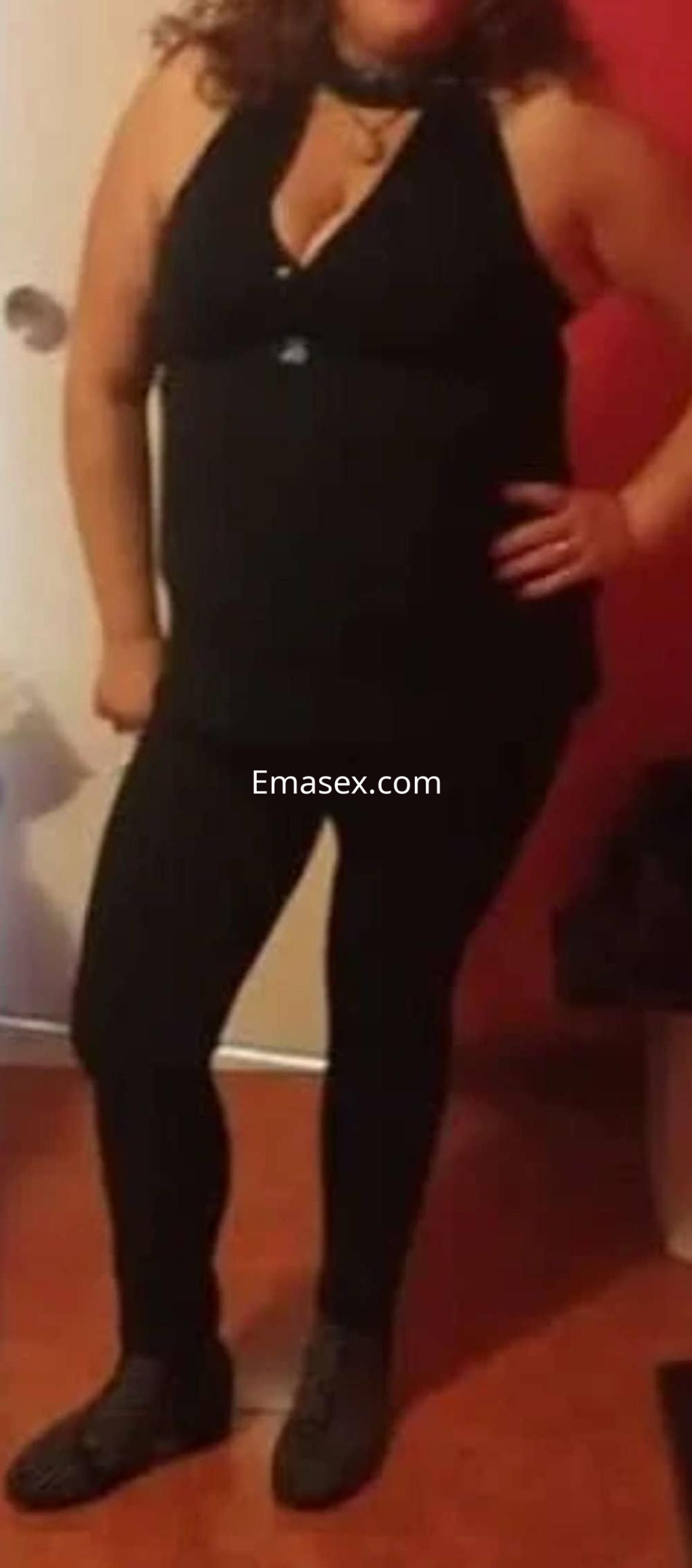 Puta con cabello rizado y oscuro, vestida con blusa sin mangas y pantalones negros en un entorno interior en Granada.