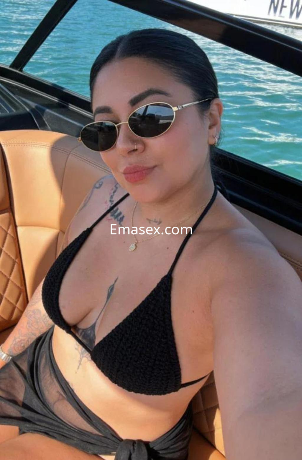 Escort en Las Palmas posando en un yate, con un bikini negro y gafas de sol, mostrando un estilo relajado.