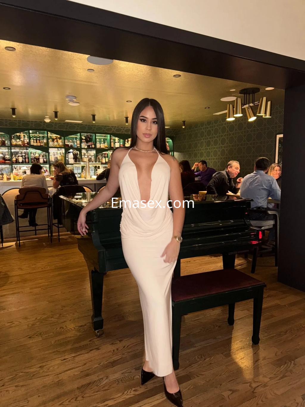 La puta posa con un vestido largo y ajustado de color nude en un elegante bar de Zaragoza.