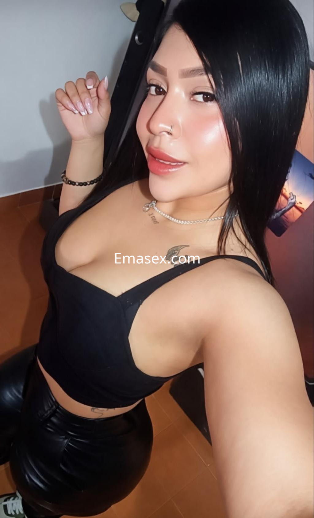 Puta en Santander con top negro ajustado y pantalones de cuero, mostrando cabello lacio y un maquillaje sutil.