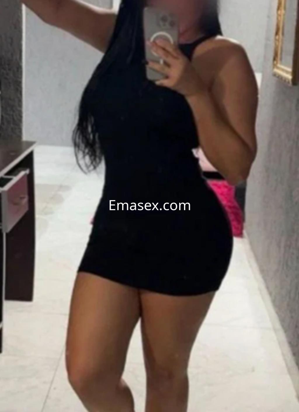 Escort en Santander posando con un vestido negro ajustado, mostrando su figura en un entorno interior.