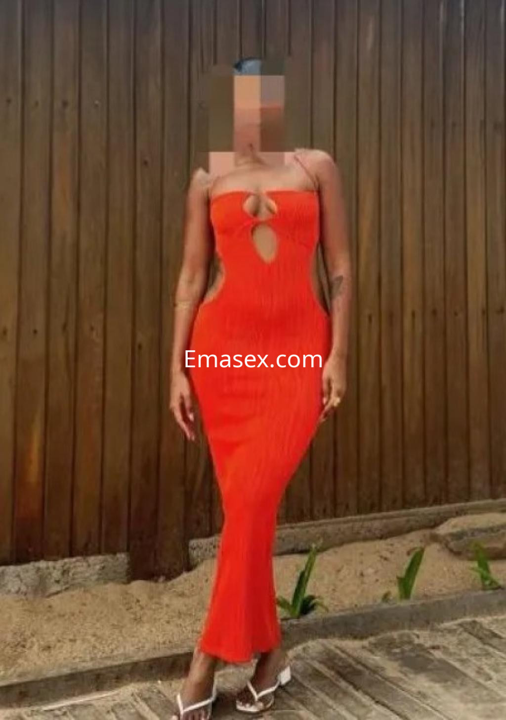 Puta con cabello corto, luciendo un vestido rojo ajustado y sandalias, posando en un entorno al aire libre en Cádiz.