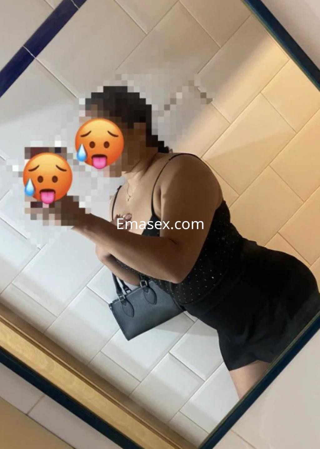 Puta de Logroño posando frente a un espejo, lleva un top negro con detalles brillantes y una falda corta.