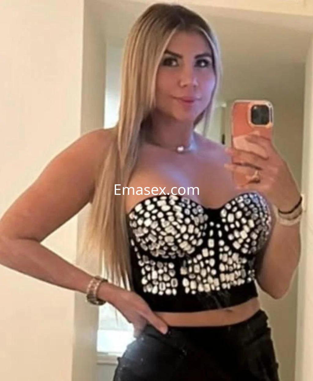 Puta con cabello largo y lacio, viste un top negro con detalles brillantes y jeans ajustados en Granada.