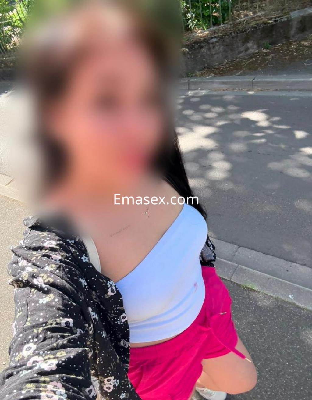 Puta en Toledo con blusa blanca y pantalones cortos rosas, posando en una calle con luz natural.