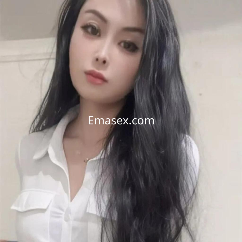Escort en Valencia con cabello largo y negro, vistiendo una blusa blanca y mostrando una expresión suave.
