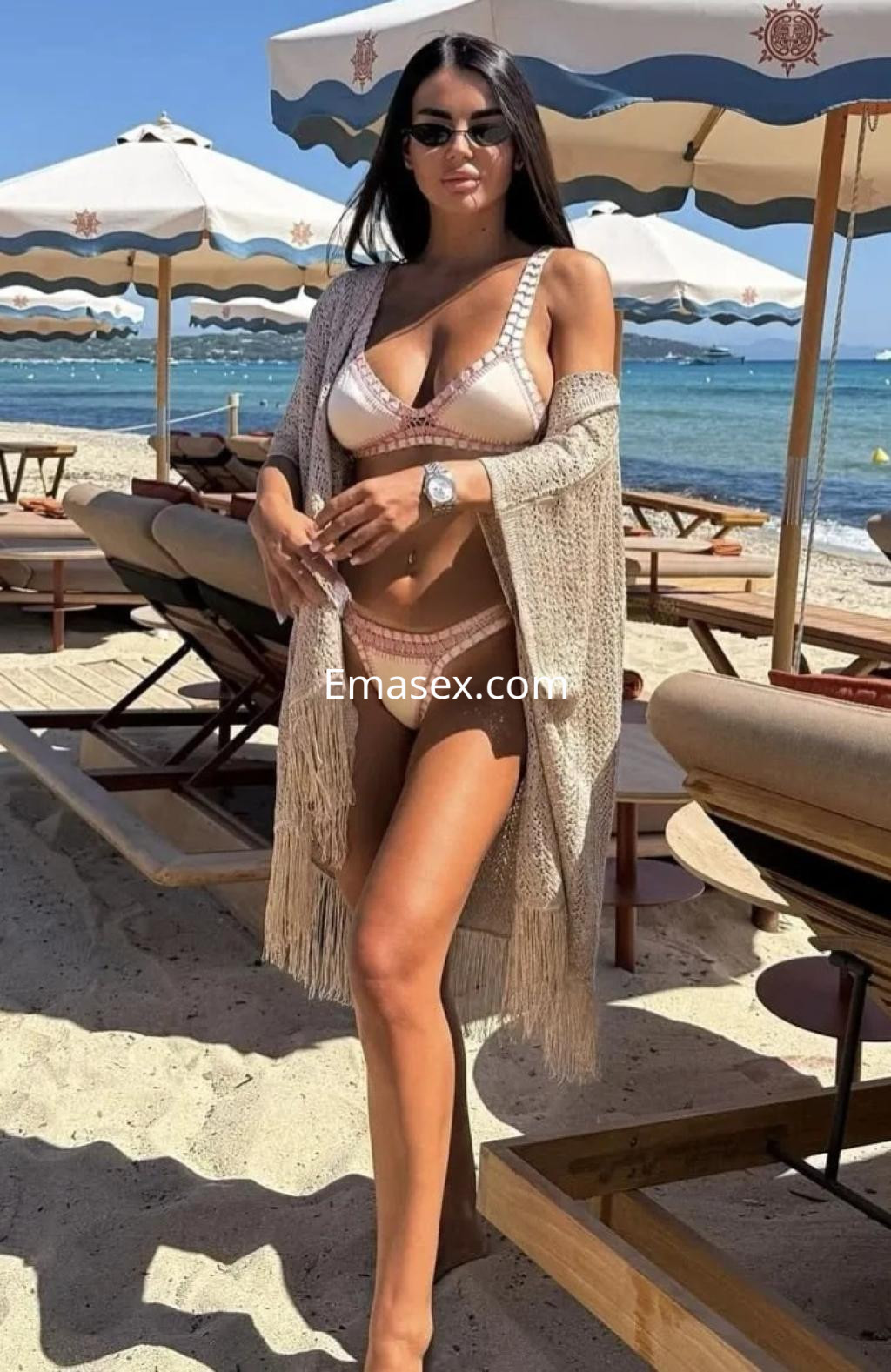 La puta posa en la playa de Alicante, luciendo un bikini blanco con detalles y un kimono ligero.