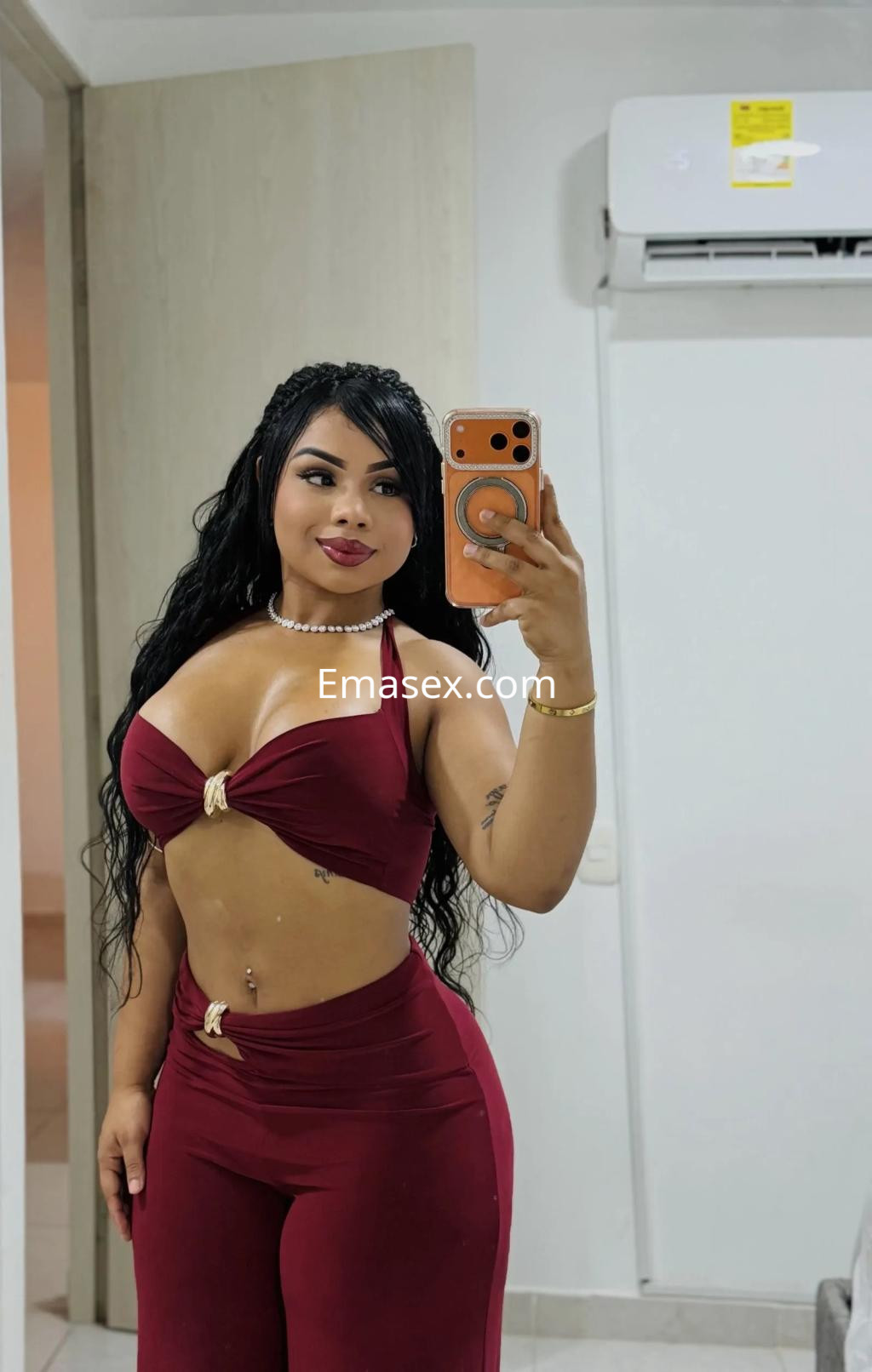 Escort en Córdoba posando con un top ajustado de color burdeos y pantalones del mismo tono, con cabello largo.