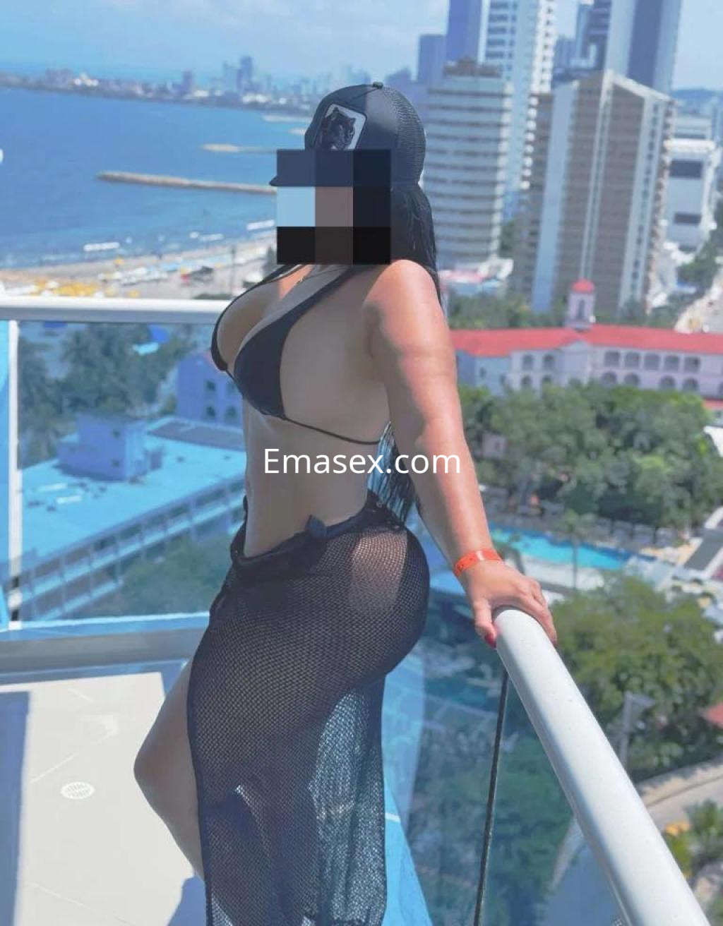Puta posando en un balcón con vista al mar, luciendo un bikini negro y una falda de red en Girona.