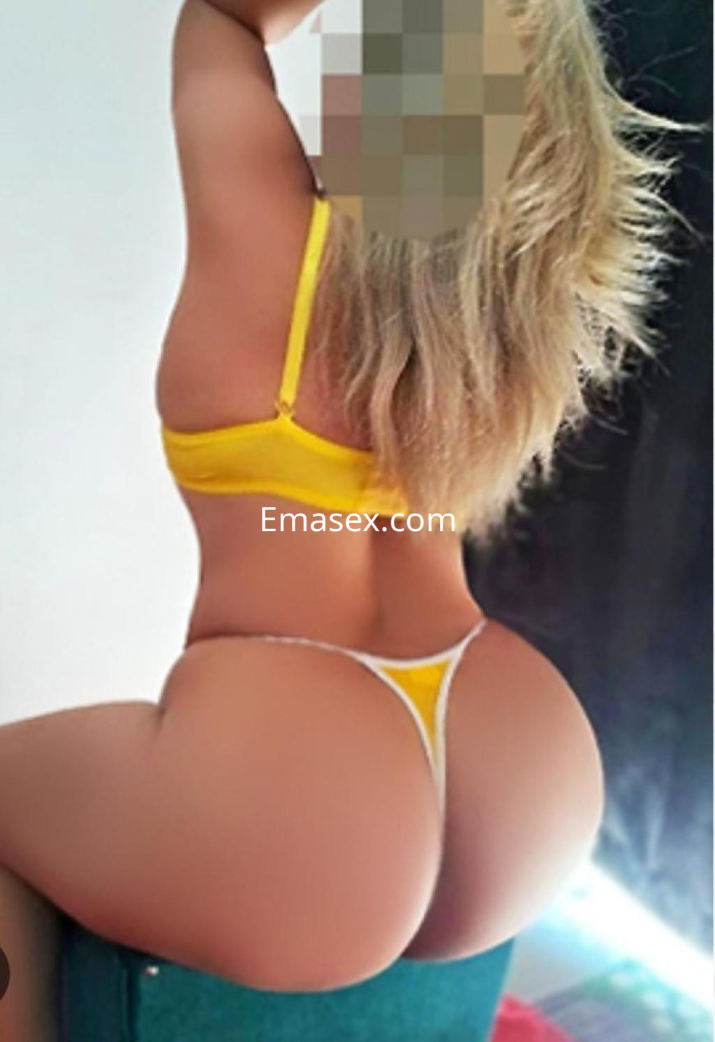 Puta posando de espaldas en Granada, luciendo un sujetador amarillo y un tanga blanco con cabello rubio.