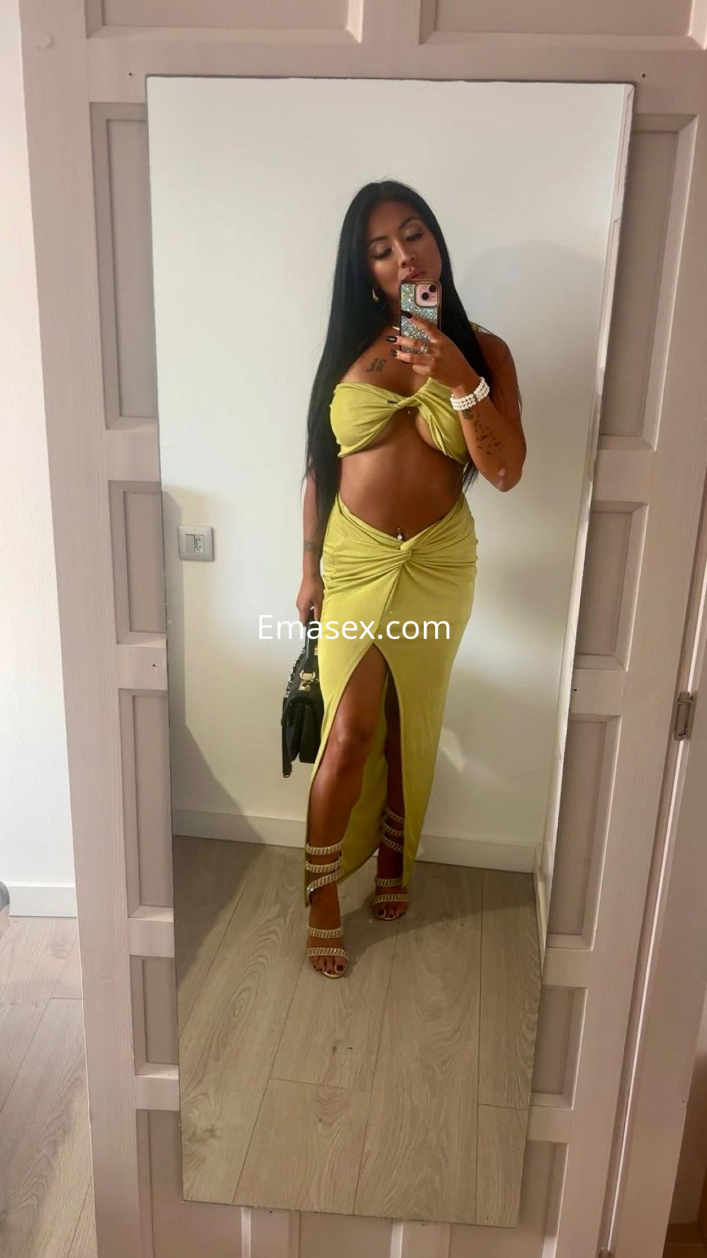 Puta en Girona viste un vestido amarillo ajustado que deja al descubierto su abdomen, con sandalias y un bolso negro.