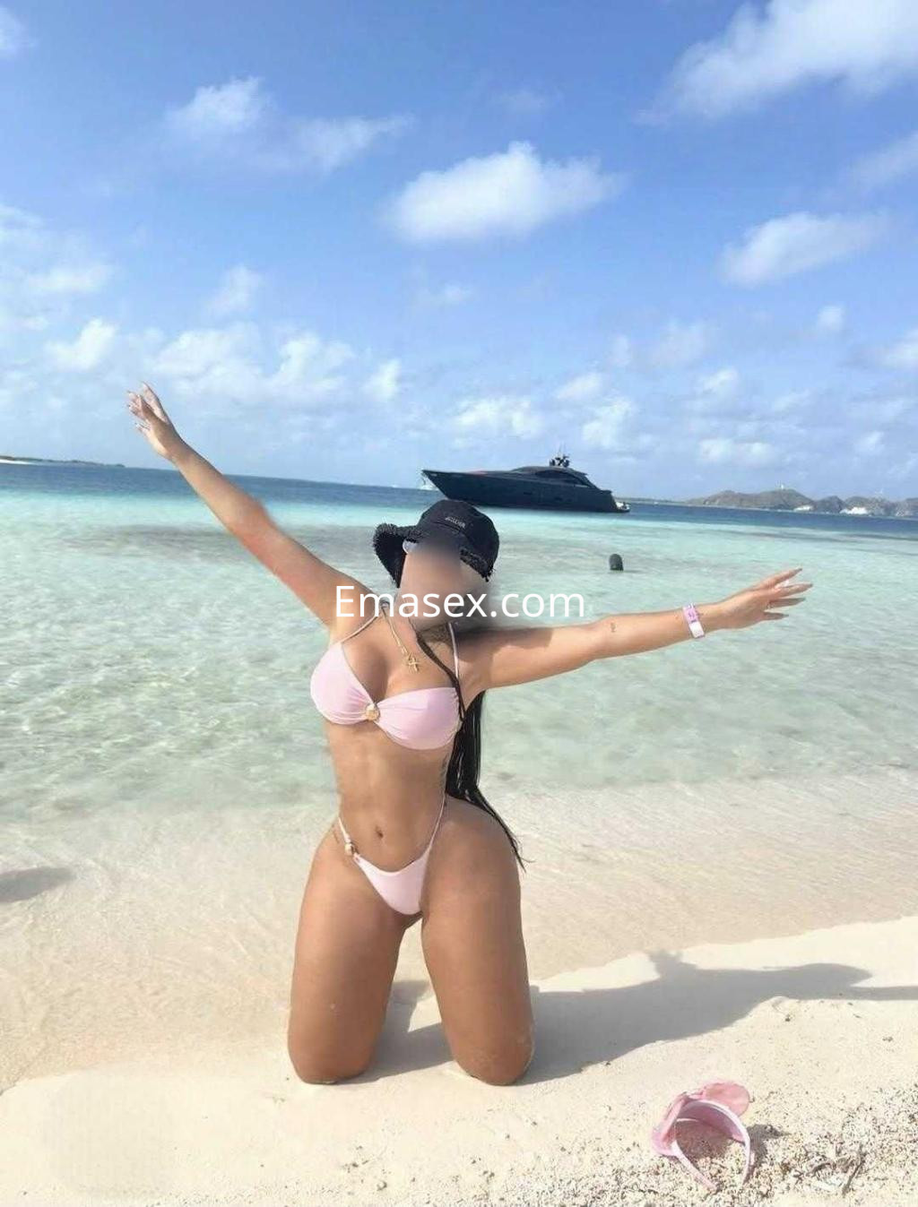 Puta posando en la playa de León, con bikini rosa y cabello largo, disfrutando del sol y el mar.