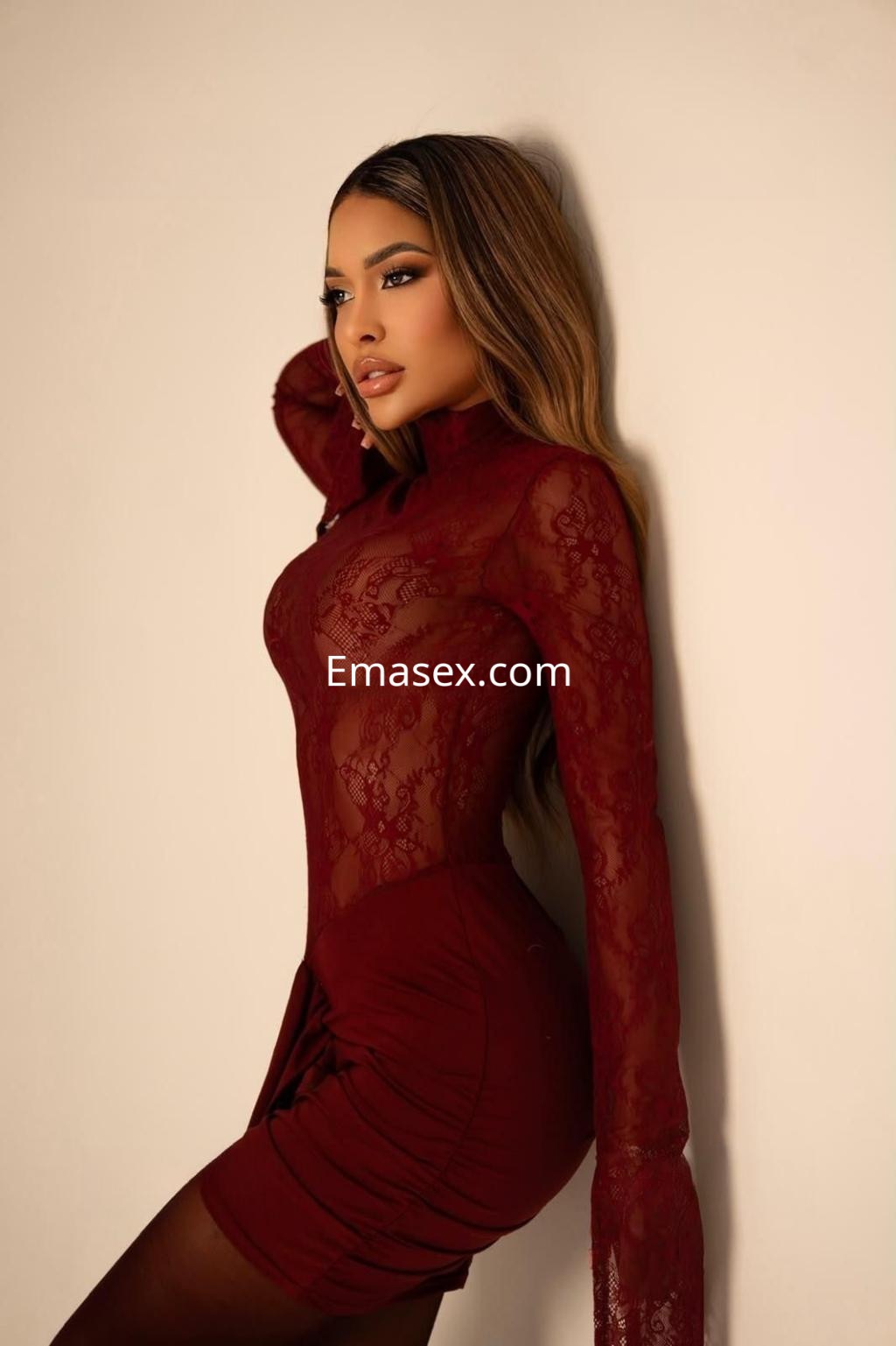 Escort en Madrid con cabello largo y lacio, vistiendo un vestido de encaje burdeos que resalta su figura.