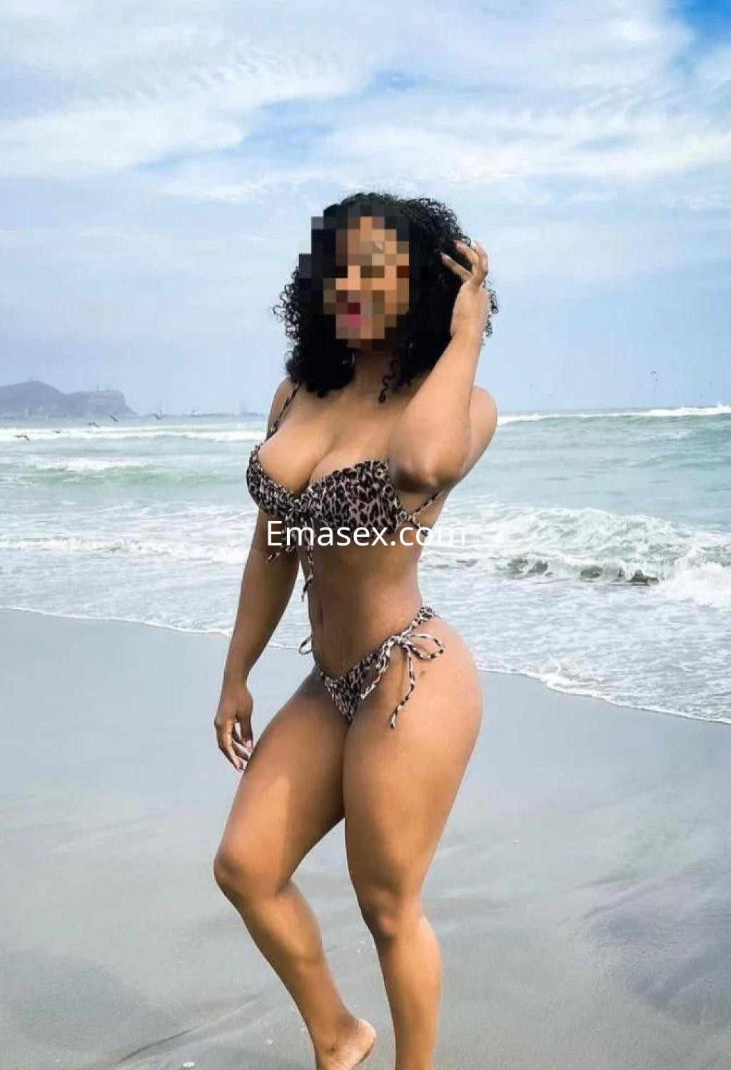 Escort en la playa de Alicante, luciendo un bikini de leopardo y posando con el mar de fondo.