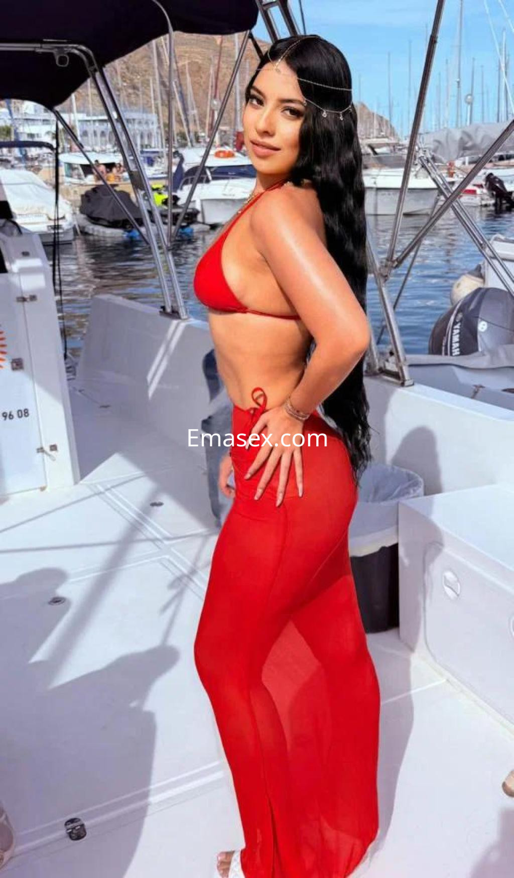 Puta posando en un yate en Almería, con un bikini rojo y una falda transparente, luciendo un cabello largo y lacio.