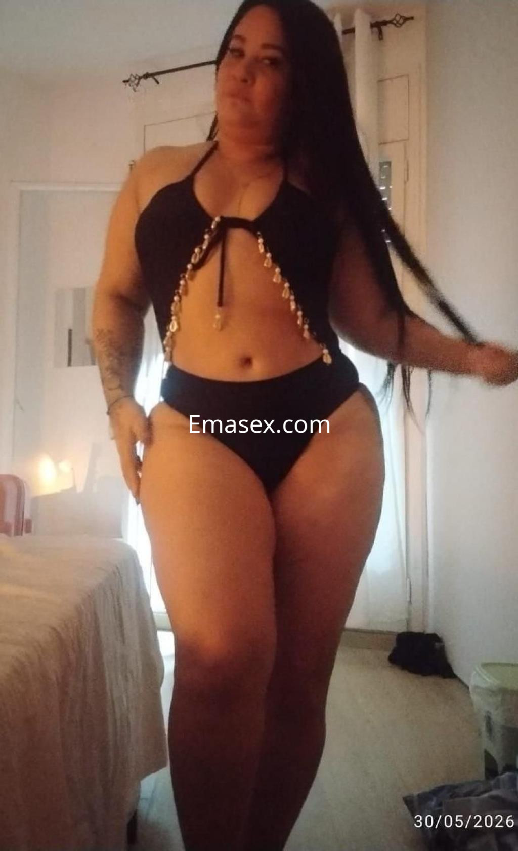 Puta de Barcelona posa con un conjunto de lencería negro, luciendo su cabello largo y una figura curvilínea.