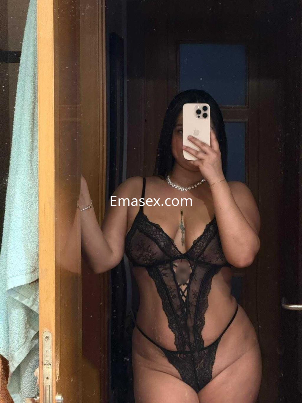 Escort en Madrid, posando frente a un espejo con lencería negra transparente y joyería sencilla.