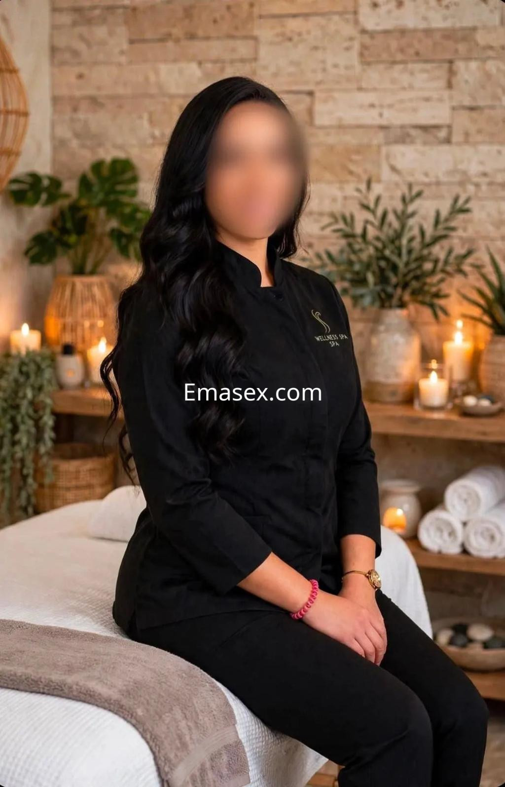 Escort en Murcia con cabello largo y oscuro, vestida con uniforme negro, sentada en un entorno de spa elegante.