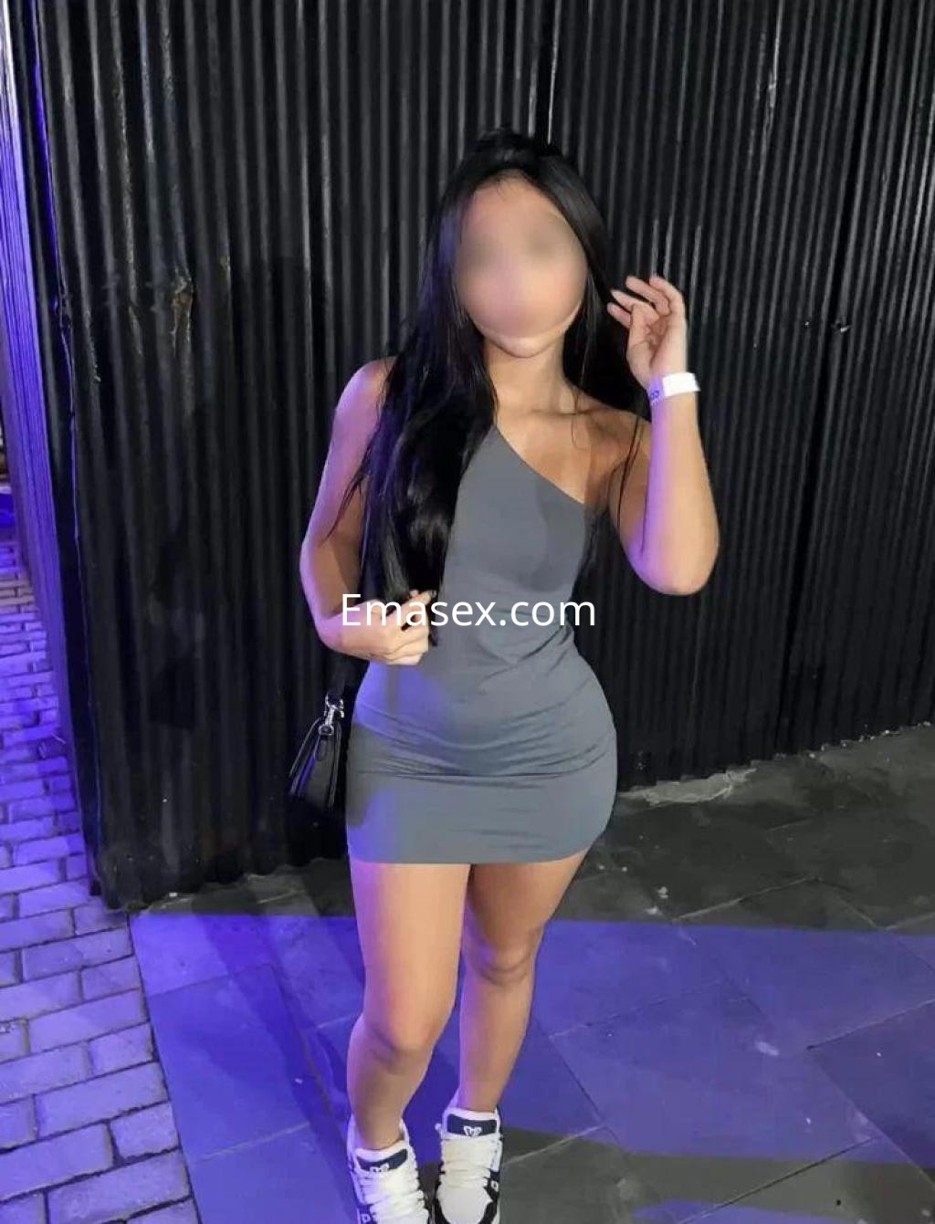Puta con vestido gris ajustado y zapatillas blancas, posando en un entorno urbano de Las Palmas.