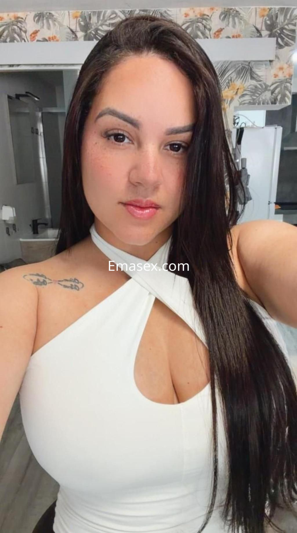 Puta de Pontevedra con cabello largo y lacio, luciendo una blusa blanca ajustada que resalta su figura.