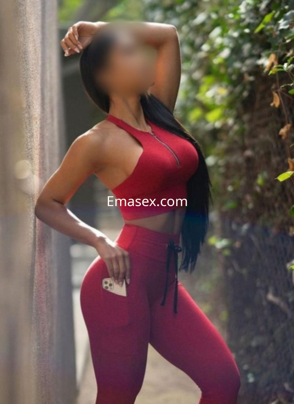 Escort en Santander luciendo un conjunto deportivo rojo, posando de lado con el cabello largo y liso.