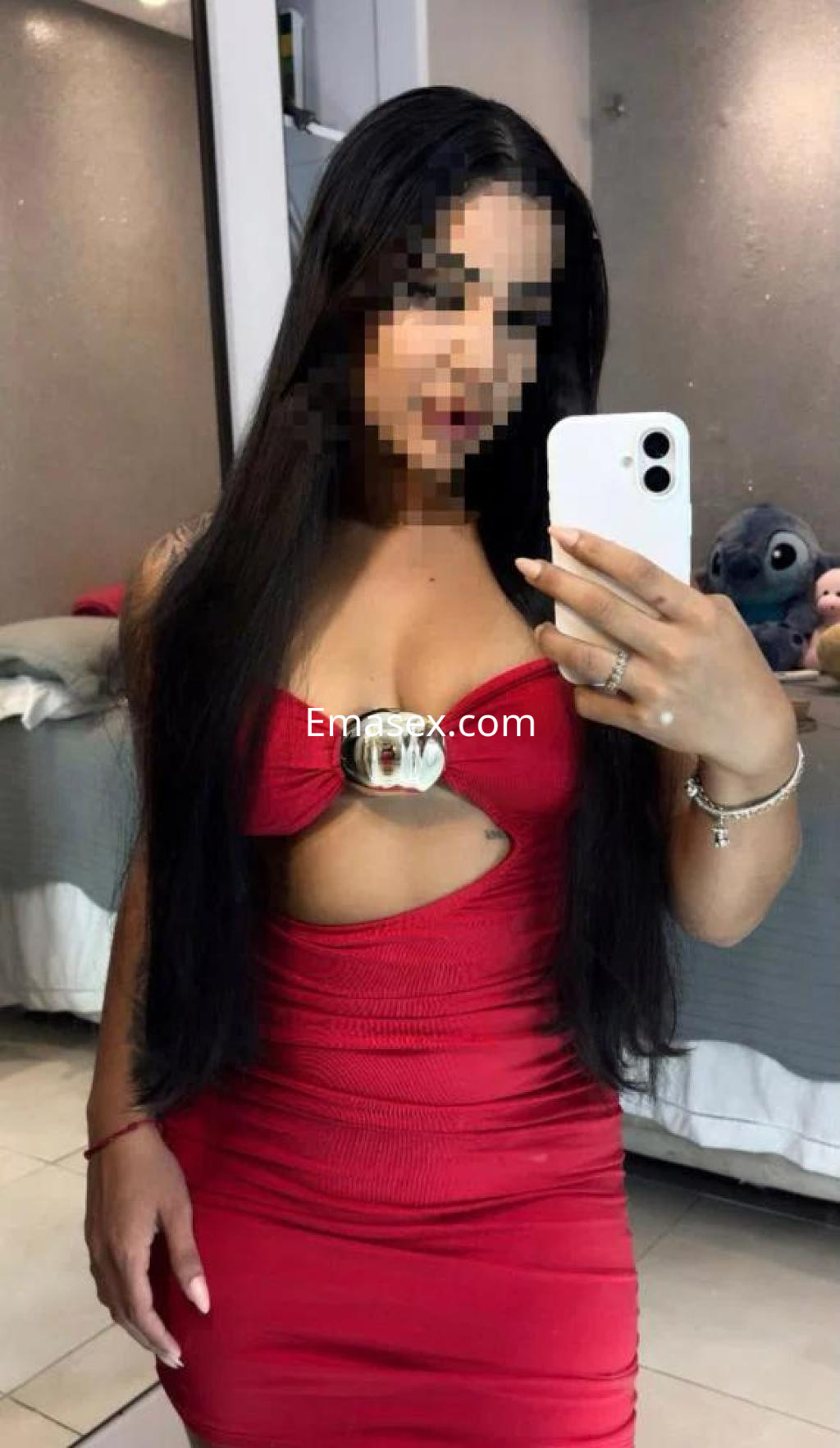 Escort en Sevilla con vestido rojo ajustado, cabello largo y lacio, posando frente a un espejo.