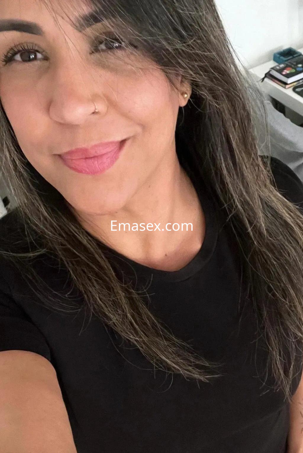 Escort en Málaga con cabello largo y suelto, vistiendo una camiseta negra y mostrando una sonrisa amigable.