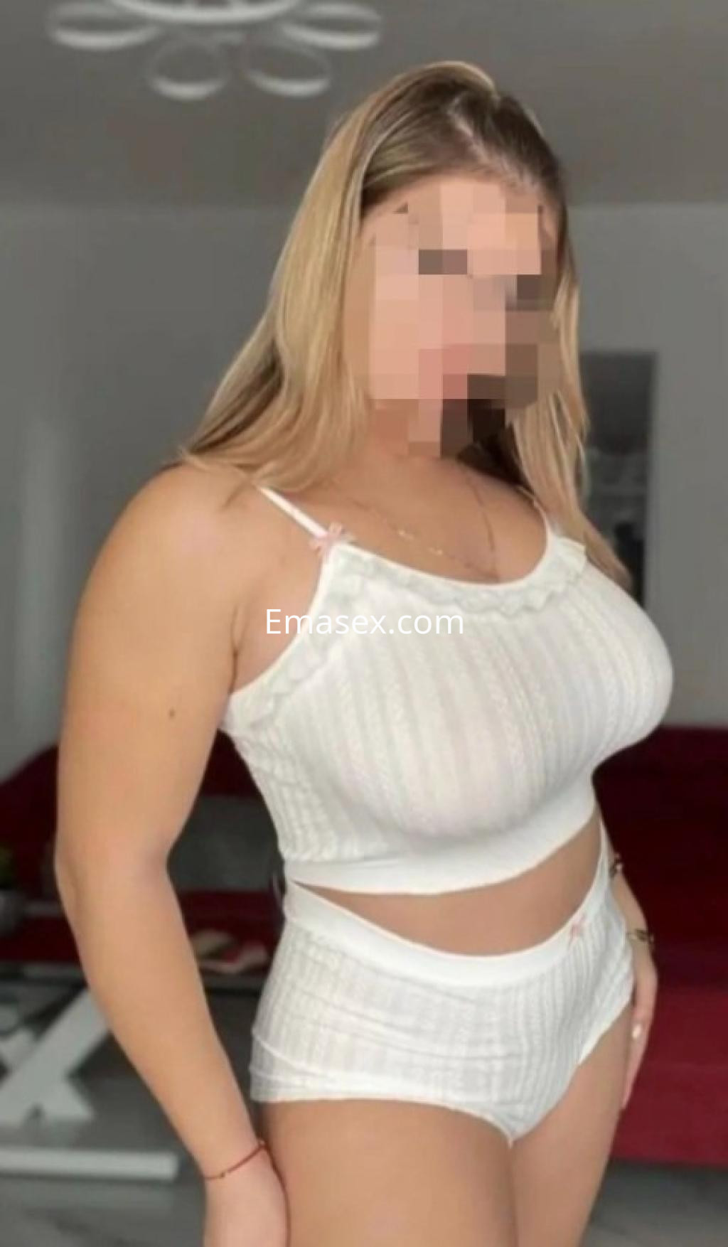 Escort en Burgos luciendo un conjunto blanco de top y short, con cabello largo y lacio, en un ambiente interior.