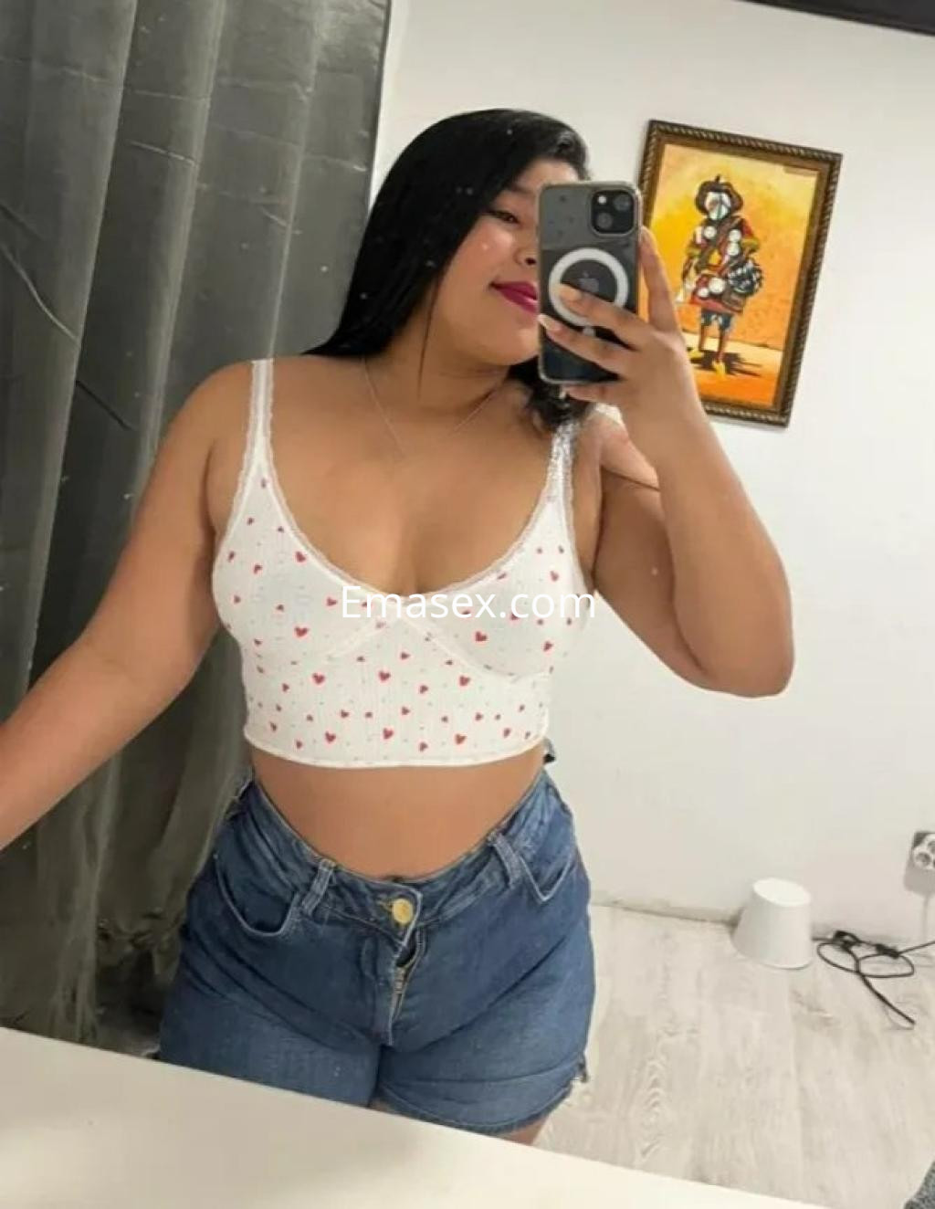 Escort en Barcelona con cabello largo y lacio, vistiendo un top blanco con corazones y shorts de mezclilla.