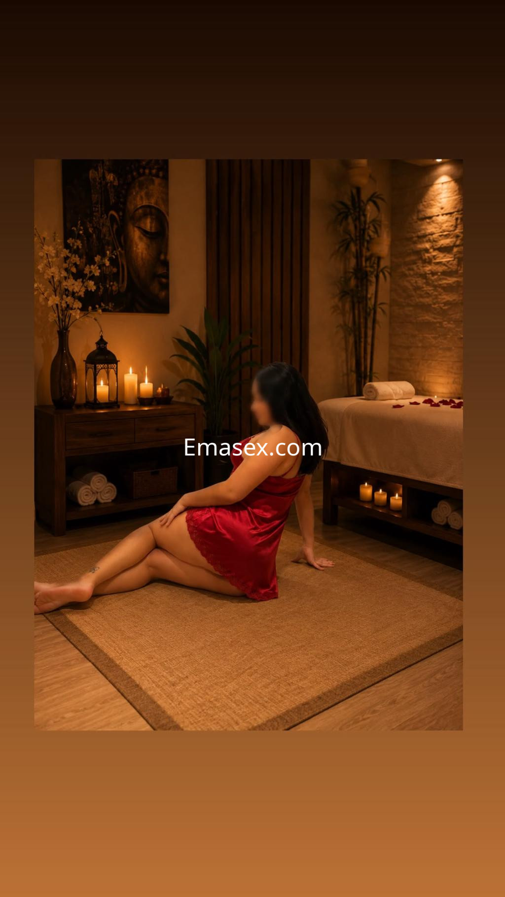 Escort en Coruña, sentada en una habitación de spa con luz tenue, vistiendo una bata roja y rodeada de velas.