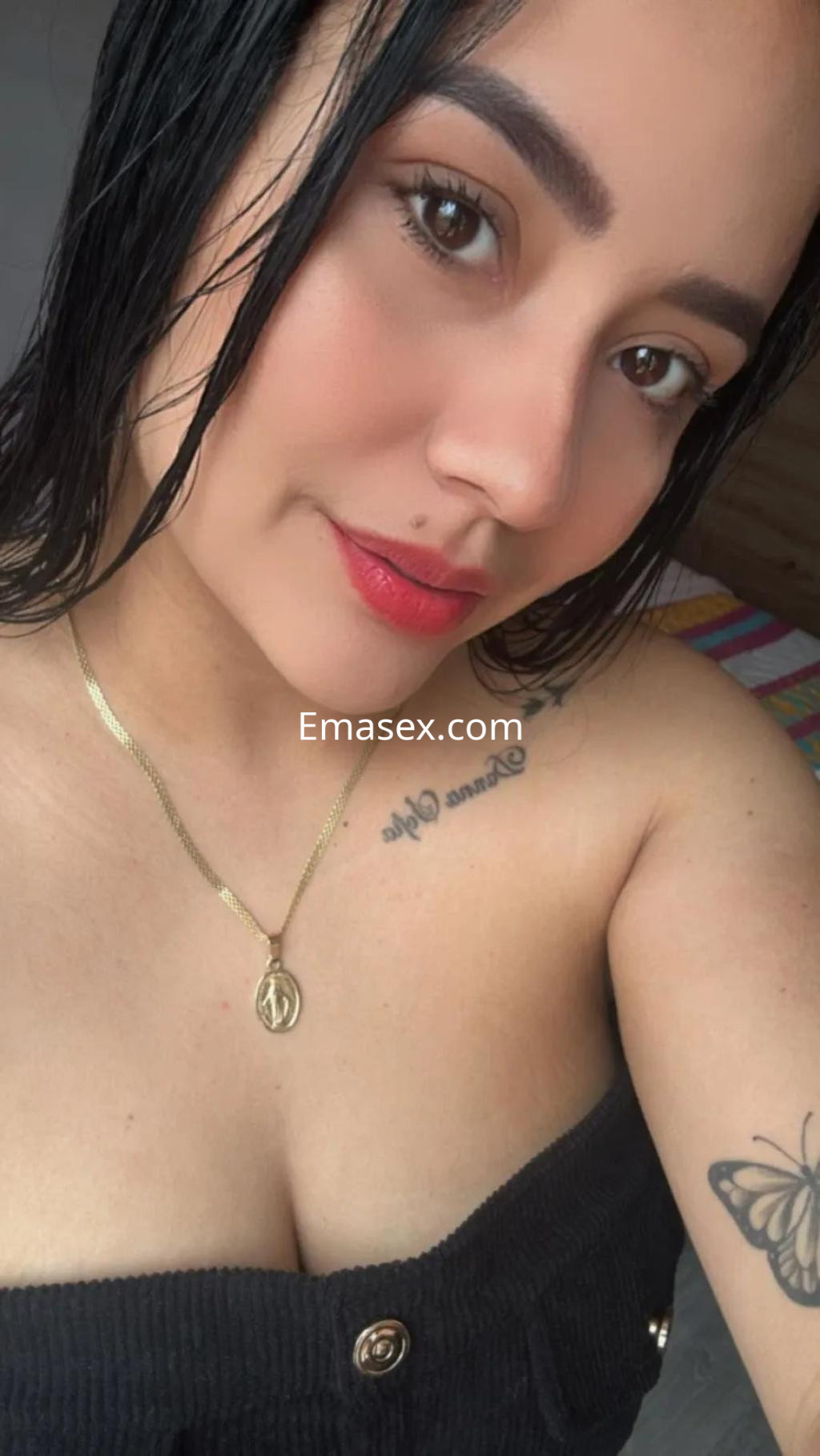 Escort en Alicante con cabello oscuro y lacio, luciendo un vestido sin mangas y un collar dorado.
