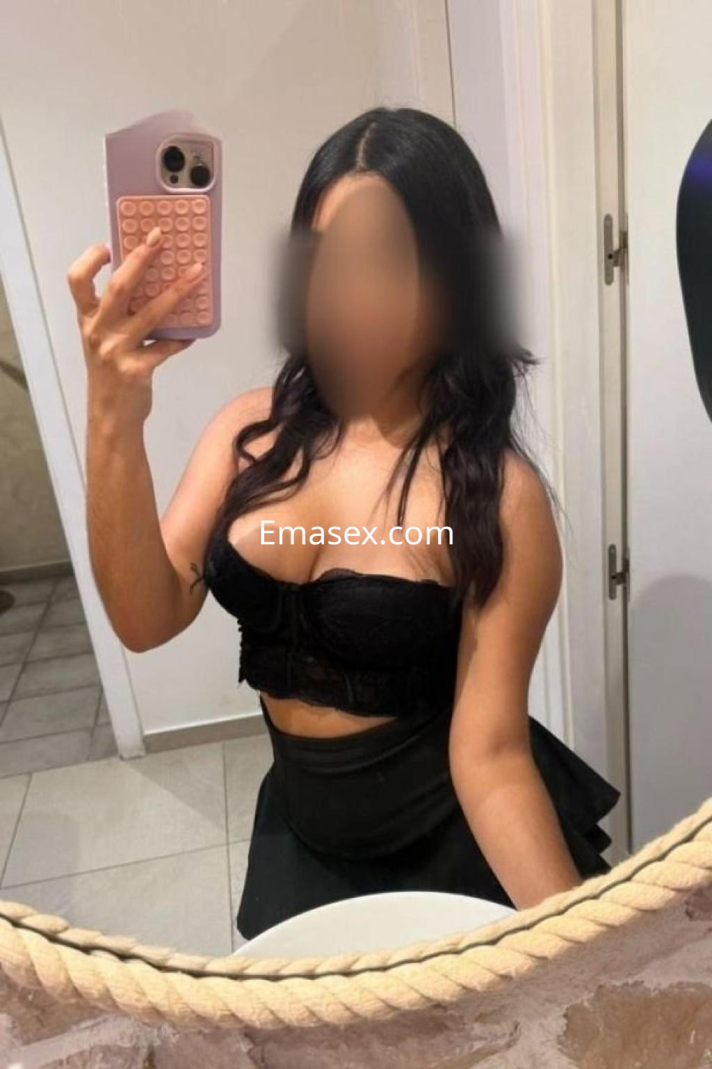 Escort en Badajoz toma un selfie en un espejo, vistiendo un top negro y una falda corta.