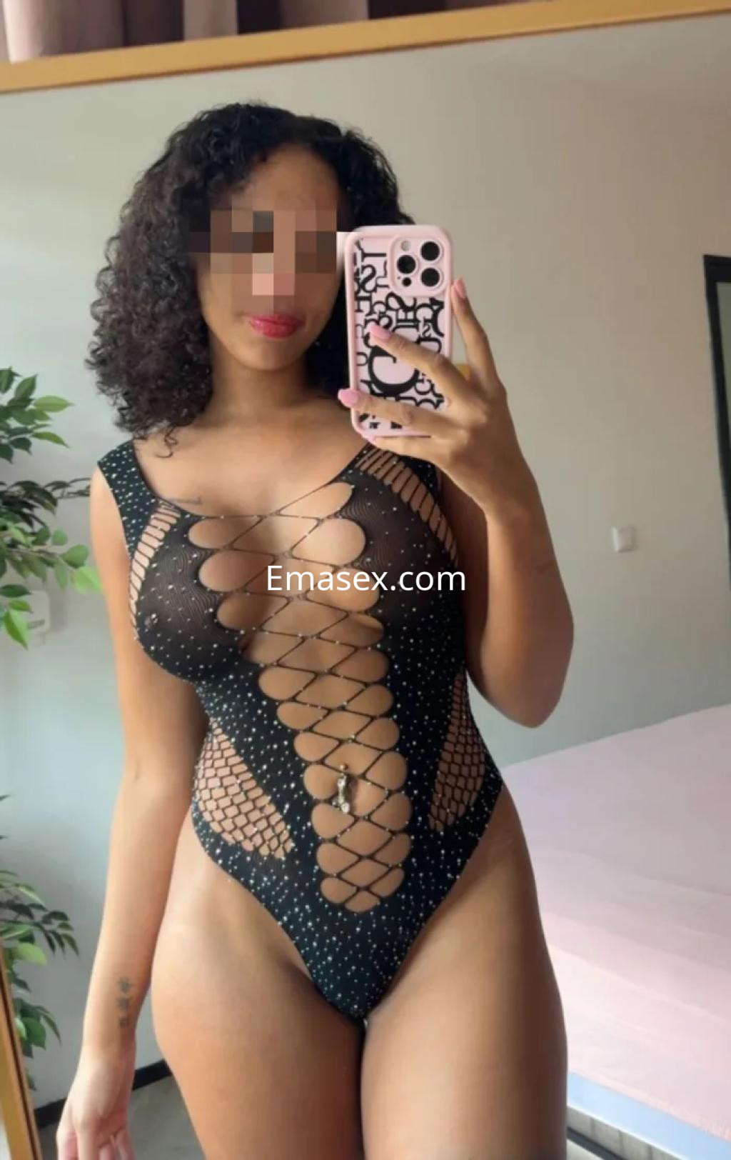Escort en Coruña luciendo un body negro con detalles en rejilla, posando frente a un espejo.