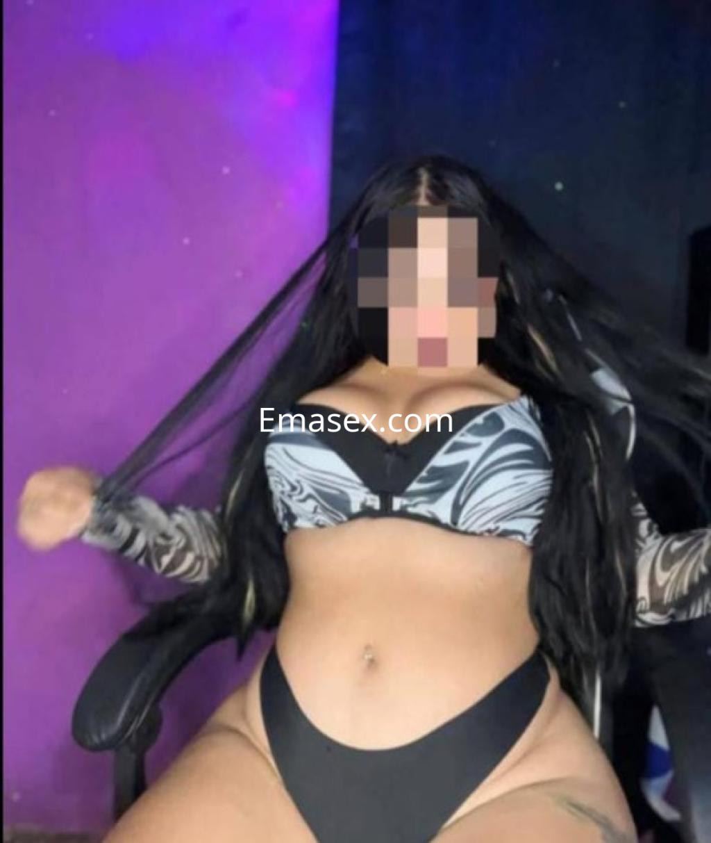 Escort en Granada con cabello largo y oscuro, vistiendo un conjunto de lencería de estampado y negro.