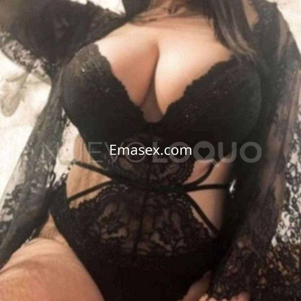 Escort en Lleida con lencería negra de encaje, posando con un abrigo transparente, mostrando confianza.