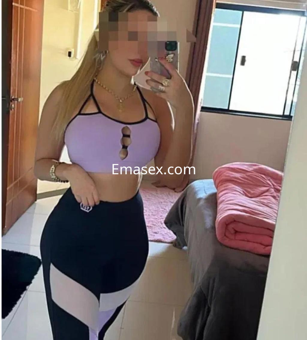 Escort en Lugo, con cabello largo y lacio, viste un top morado y leggings negros con detalles traslúcidos.