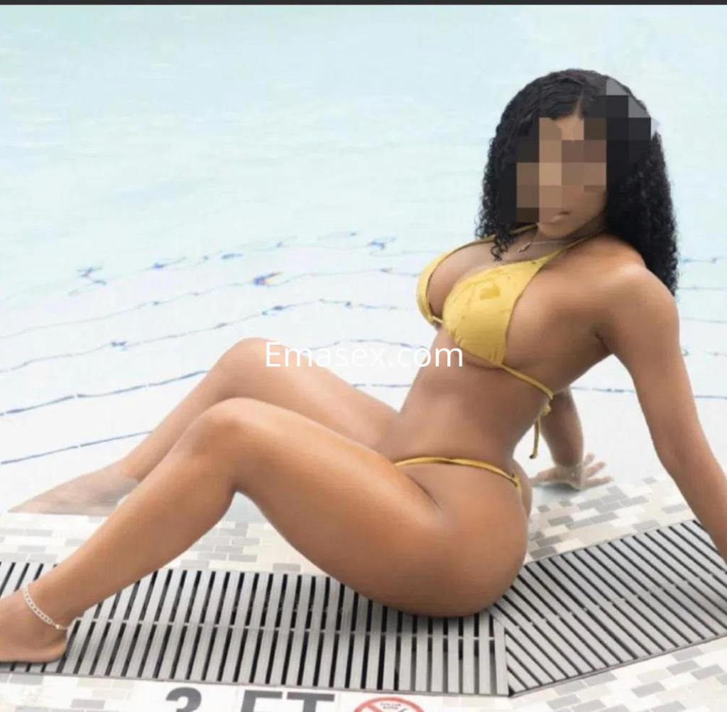 La puta está sentada en el borde de una piscina en Tenerife, vistiendo un bikini amarillo y mostrando su piel bronceada.