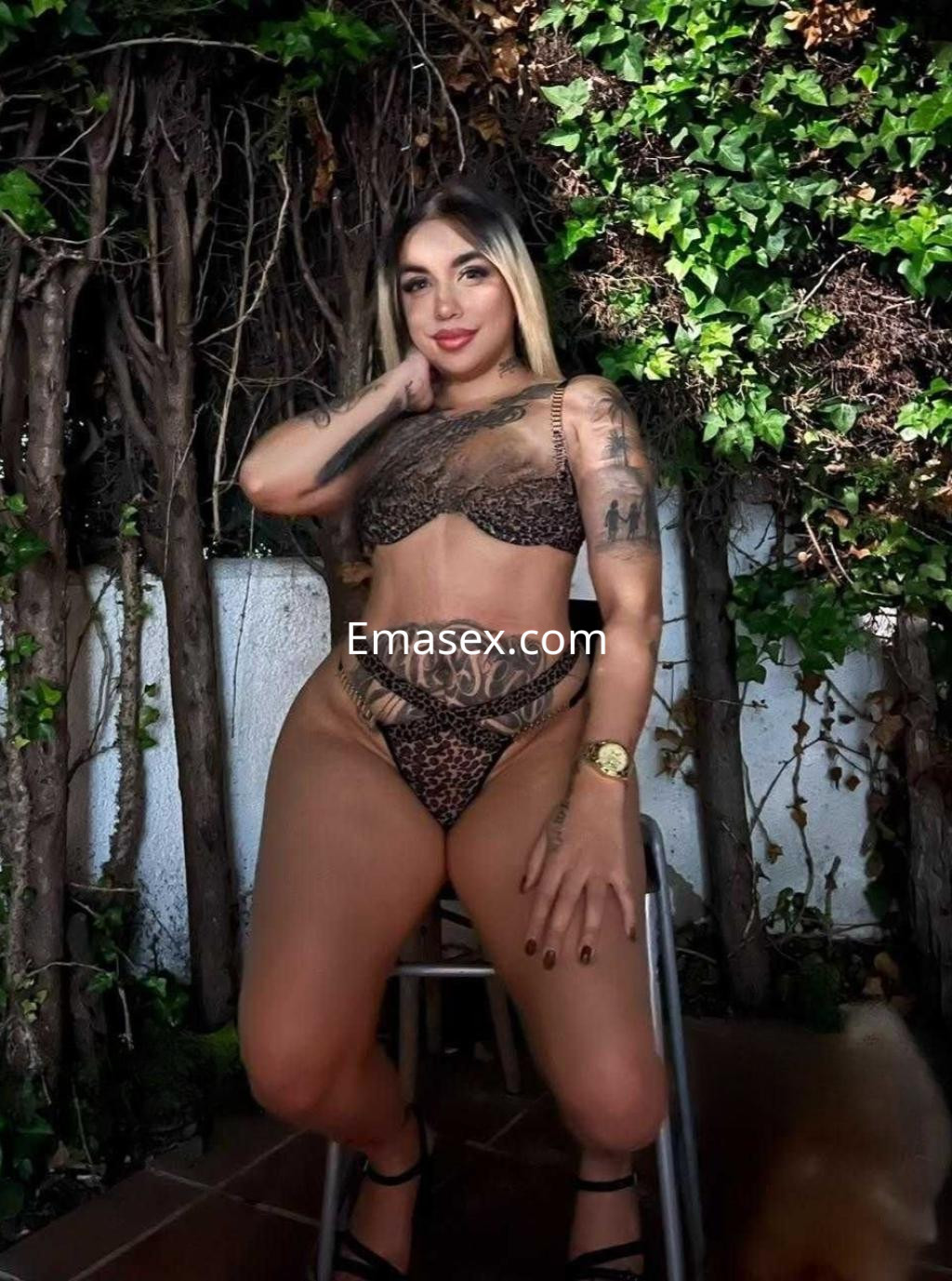La puta posa con lencería de estampado animal en un entorno natural en Huelva, mostrando sus tatuajes.