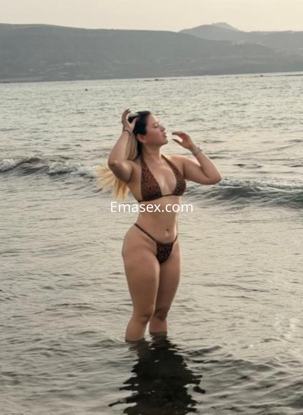 Escort en Las Palmas luciendo un bikini de leopardo mientras se sumerge en el agua del mar.