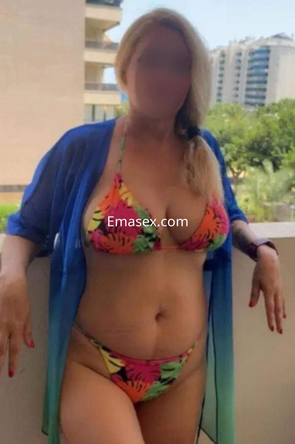 Puta en Santander luciendo un bikini colorido con estampado tropical y una chaqueta transparente.