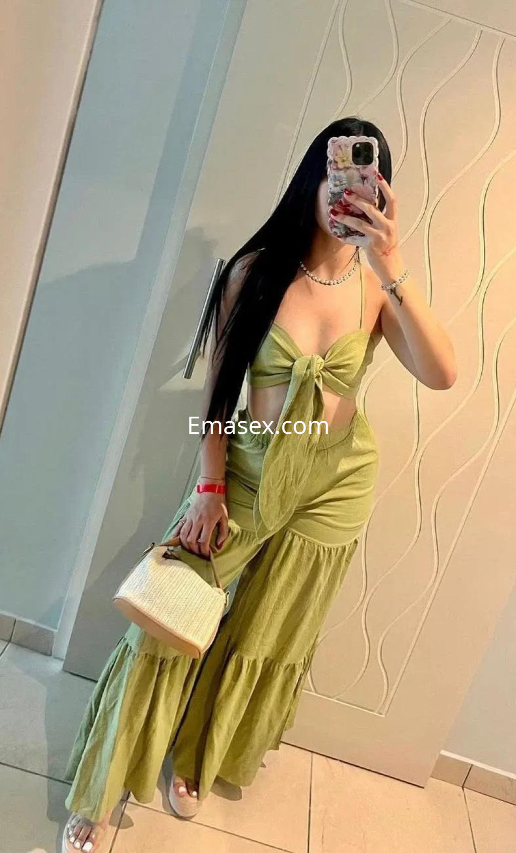 La puta luce un conjunto verde claro con un top nudo y pantalones de tirantes, sosteniendo un bolso en Cádiz.