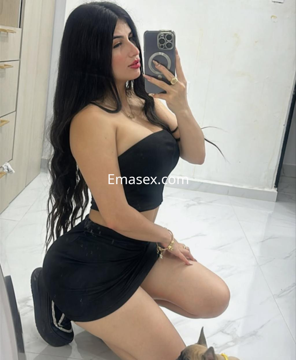 Puta en top negro y falda corta, posando de rodillas en un espejo, con cabello largo y lacio en Burgos.