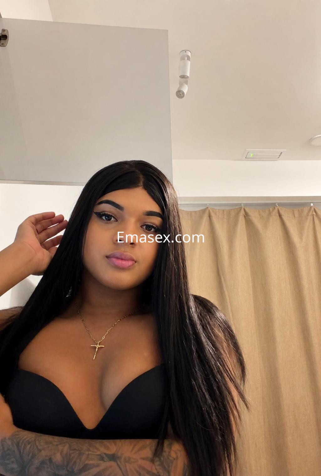 Puta trans en Madrid, con cabello largo y lacio, usando un sujetador negro, mirando a la cámara con una expresión seductora.