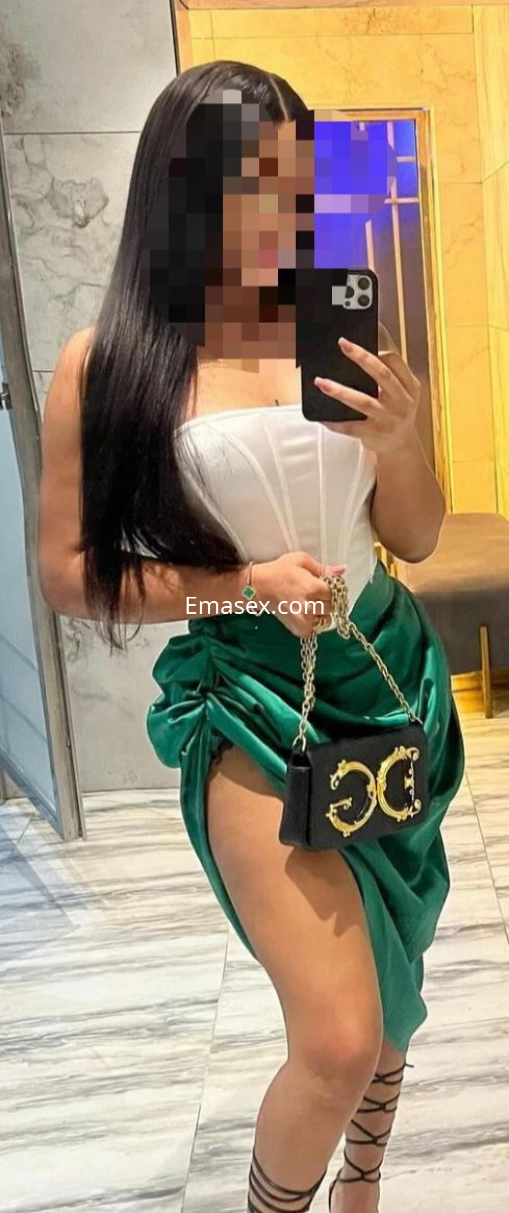 Puta con cabello largo y lacio, viste un corsé blanco y una falda verde, sosteniendo un bolso negro en Córdoba.