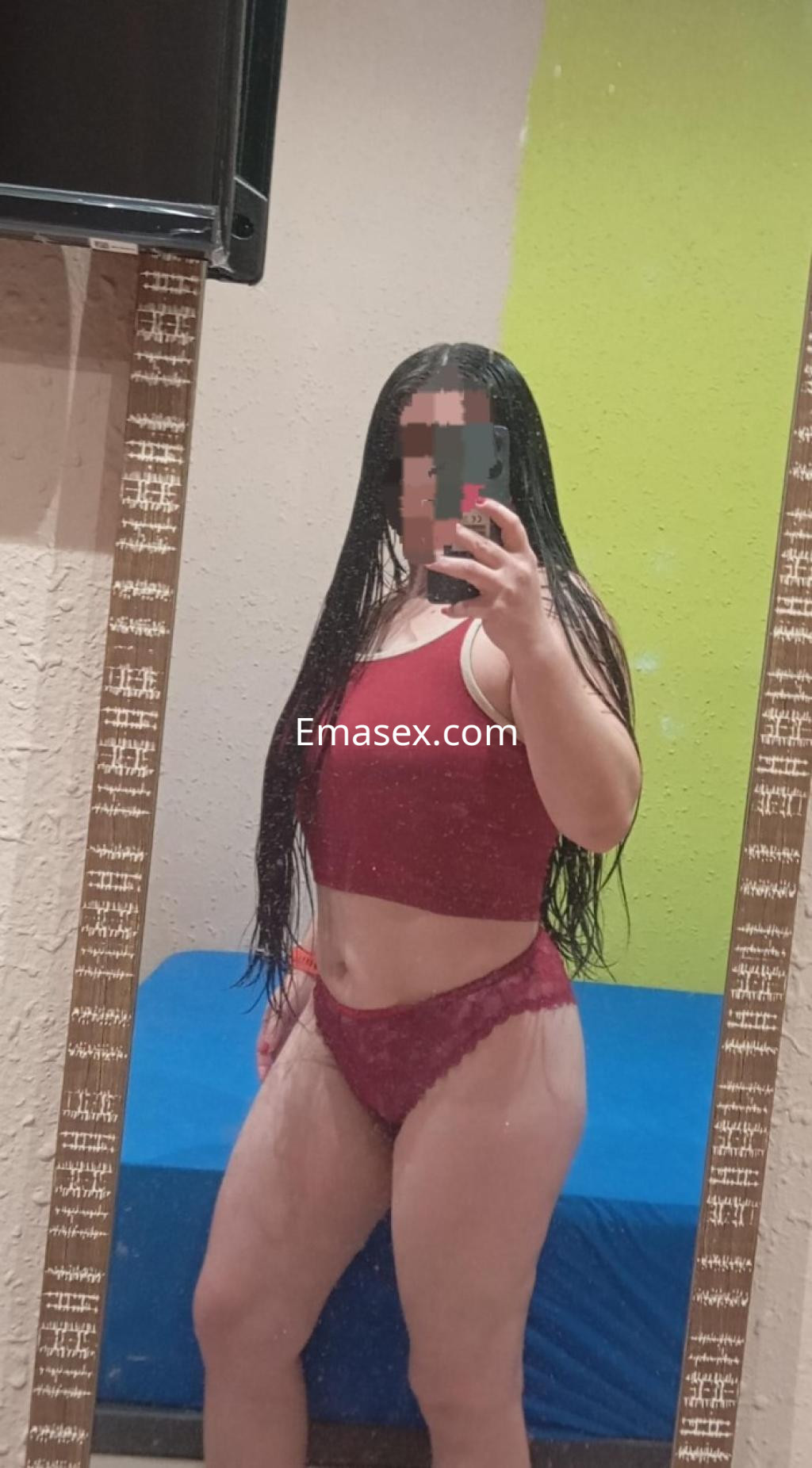 Puta en Lleida, posando frente al espejo con top rojo y ropa interior de encaje, cabello largo y lacio.
